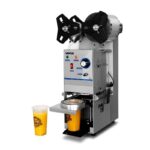 Selladora de vasos VSV-680 de Ventus en acción, sellando un vaso de bebida con precisión y eficiencia. La máquina muestra su diseño compacto y moderno, ideal para negocios que buscan mejorar la presentación y seguridad de sus productos.
